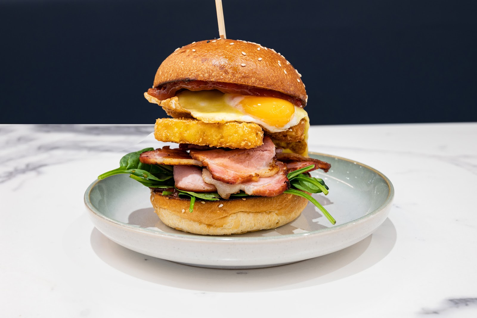 Ariel's loaded breakfast burger — bacon, fried egg with a runny yolk, hash brown and spinach on a sesame bun