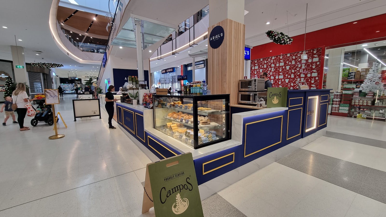 The Ariel's kiosk inside Dapto Mall — royal blue counter with gold trim, pastry cabinet, Campos A-frame sign